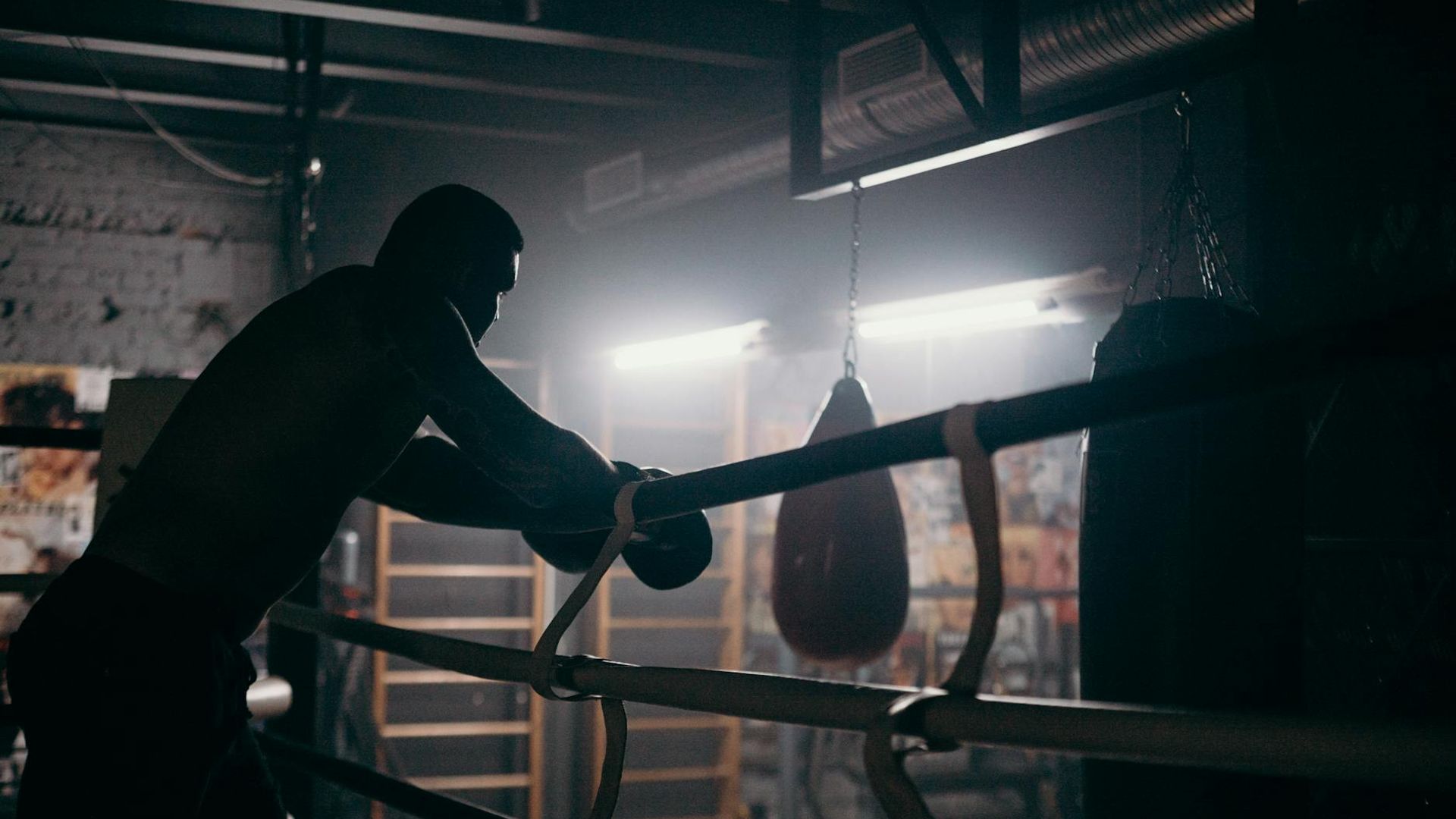 Man performing a controlled strength exercise in a dark, atmospheric gym.